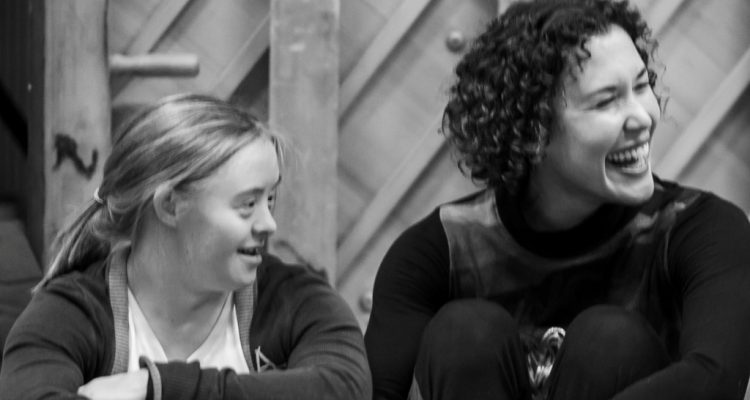 A black and white photo of Hannah Sampson and Amy Butler, they both look to their left, Amy has a big grin.