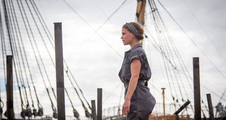 Siobhan during the Seafarers, she stands tall with ship masts and rigging in the background.