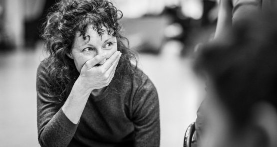 Black and white photo of Lucy Bennett, laughing, covering her mouth with her right hand.
