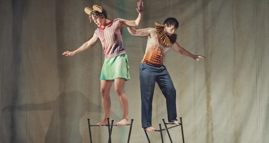 A photo from Artificial Things (2014) with two standing dancers balanced on upturned stools.