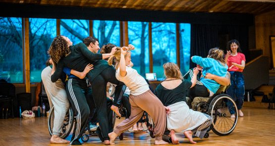 A group of disabled and non-disabled dancers together in a dance studio