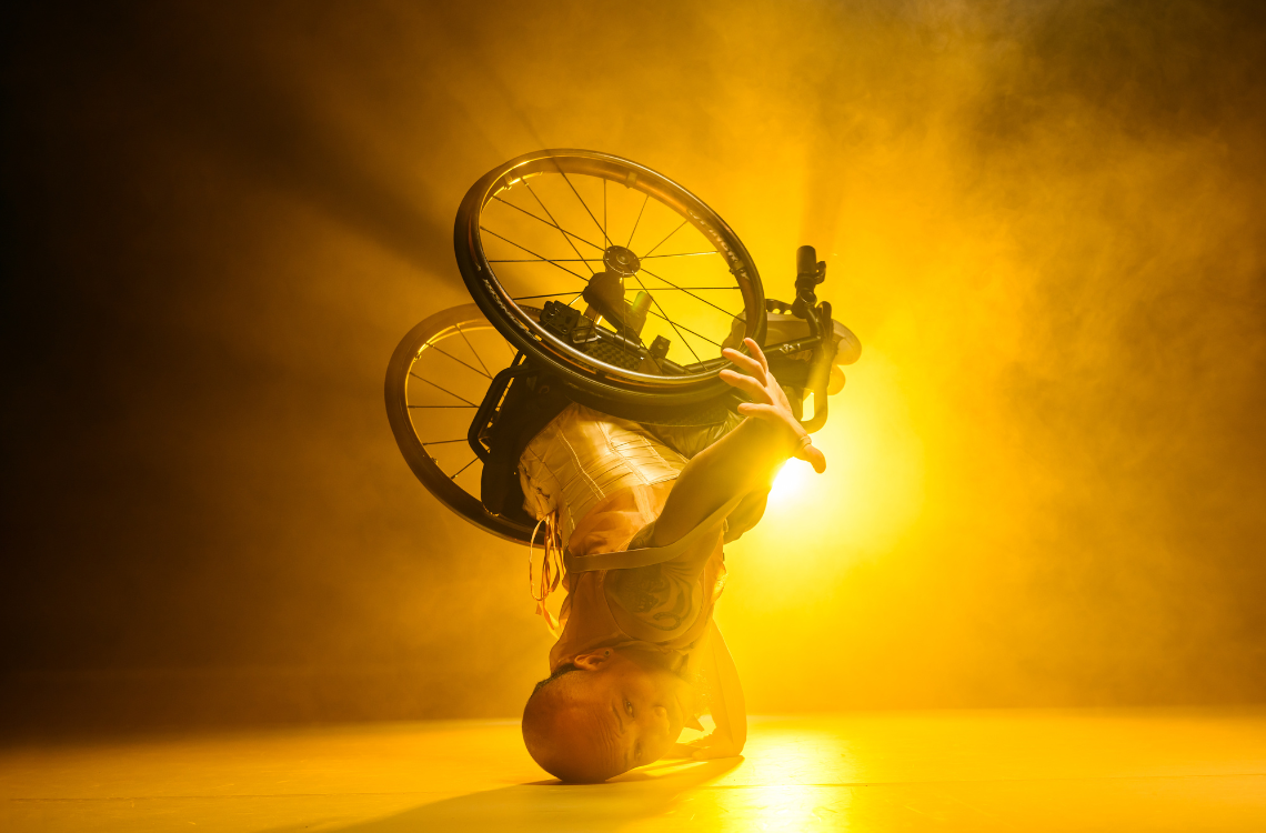 Wheelchair dancer Nadenh Poan in a gravity-defying headstand.