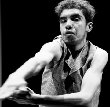 a dancer in black and white reaches to the front corner