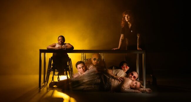 Lived Fiction performers some standing or sat at a table and the rest arranged in a fan shape beneath