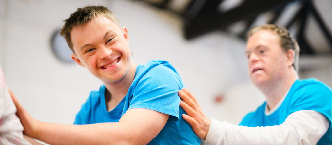 A young man with Down syndrome smiles at the camera.