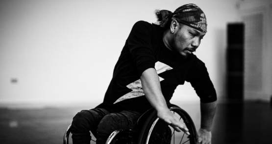 A black and white image of Nadenh, a British-Cambodian wheelchair dancer.
