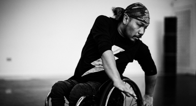 A black and white image of Nadenh, a British-Cambodian wheelchair dancer.